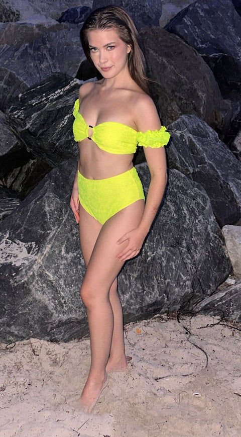 Model wearing luxury three-piece swimsuit with high-waisted bottom and lace details