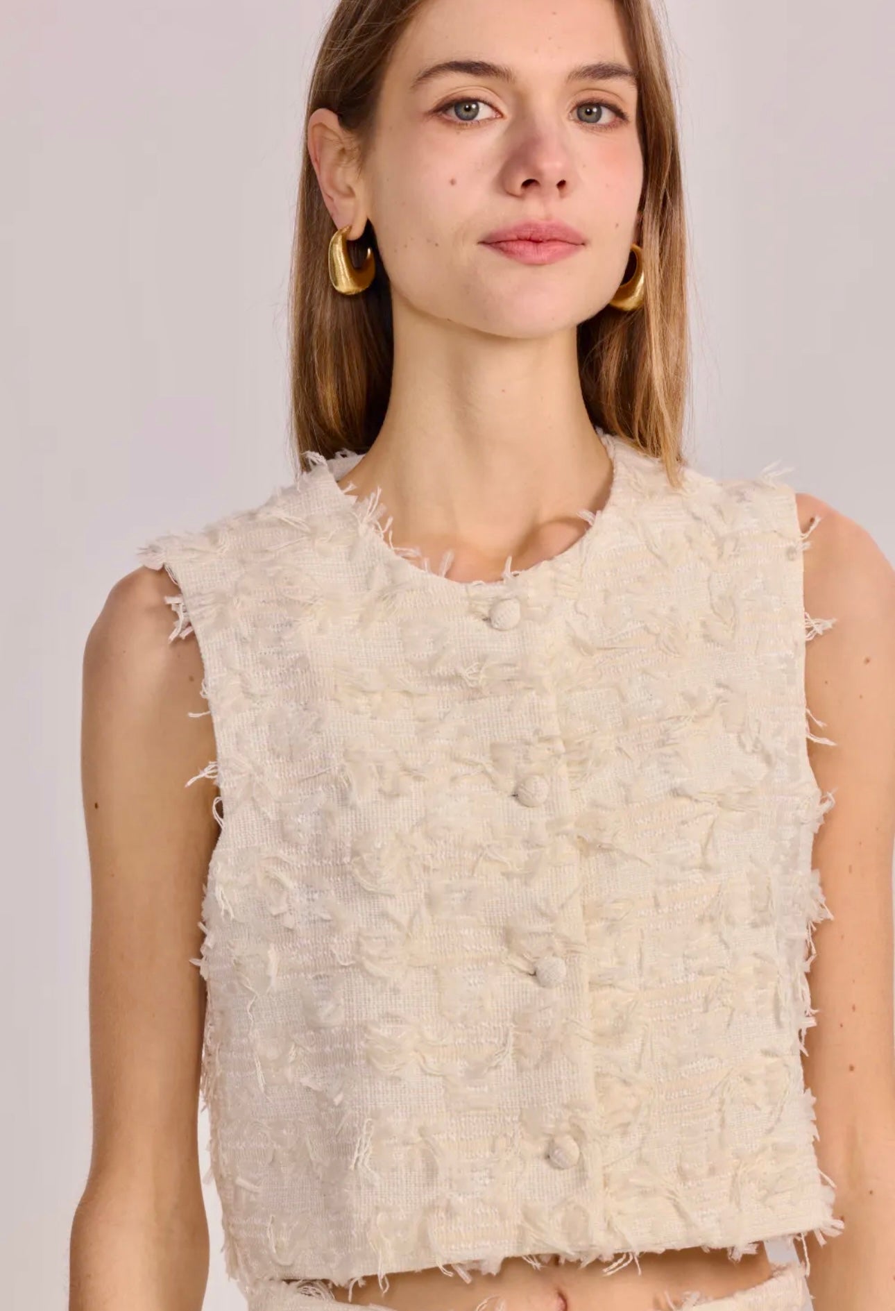Detailed view of The Gabrielle Vest in cream featuring button closure and smooth texture