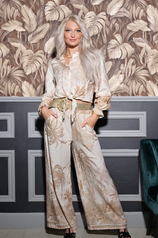 Woman in a floral outfit standing against a decorative wall.