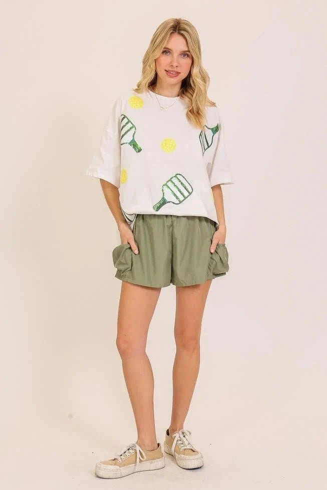 Sequin Pickleball oversized white cotton T-shirt with green paddles and yellow balls, relaxed dropped-shoulder fit