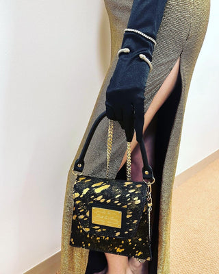 Designer handbag featuring magnetic closure and branded duster bag