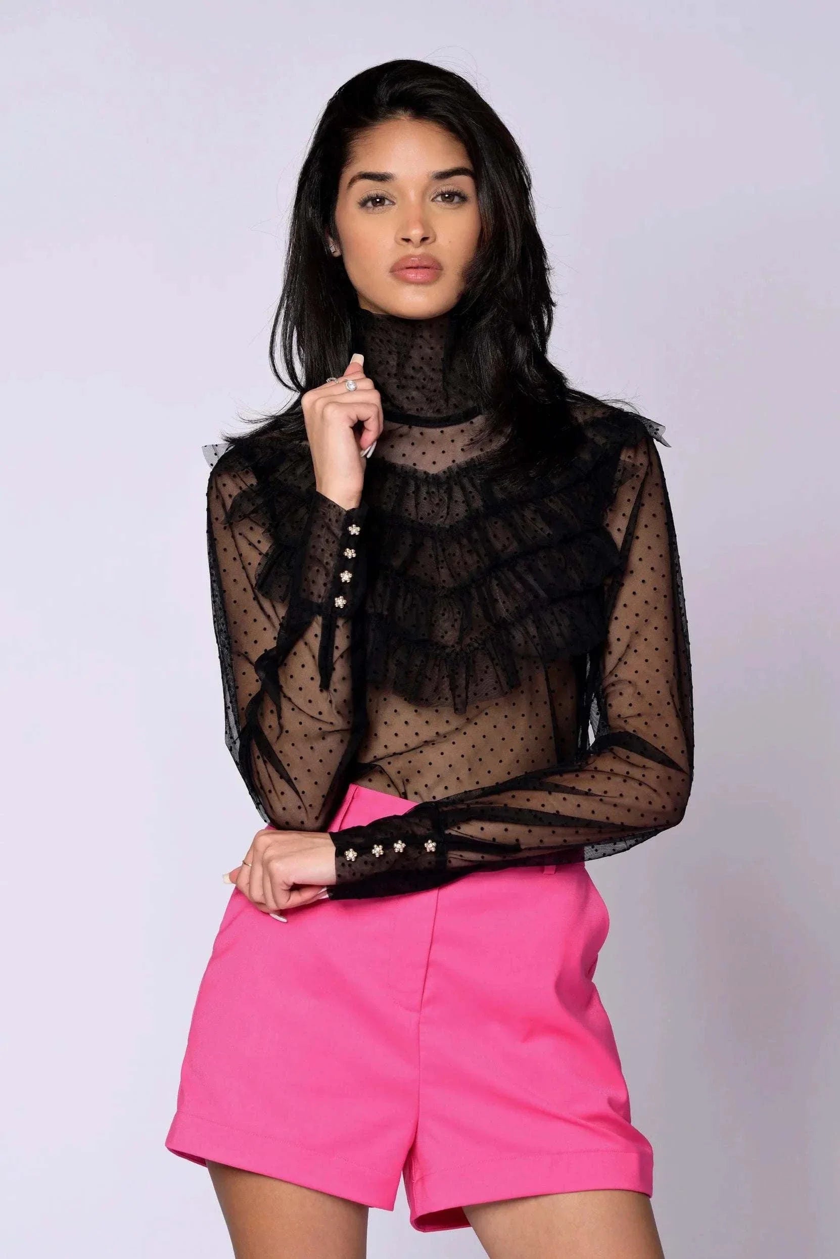 The Juliette Blouse black lace with sheer polka dot pattern, tiered ruffles, high turtleneck, long sleeves, and gold button closures
